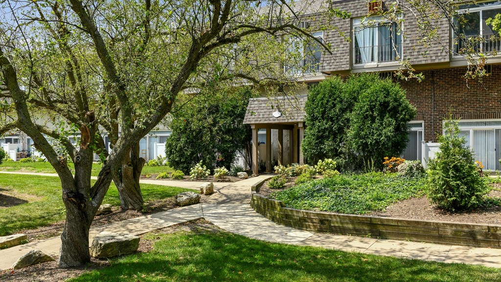 a house with a walkway and trees in front of itat Fox Run Apartments, St. Charles, 60174