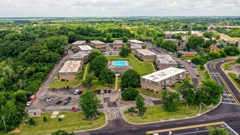 An aerial view of a parking lot with a building and a pool.