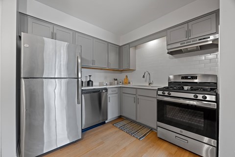 A modern kitchen with stainless steel appliances and wooden flooring.