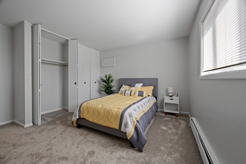 A bedroom with a bed, nightstand, and a plant.