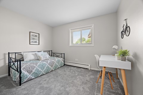 A bedroom with a bed, desk, and a window.