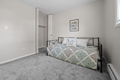 A bedroom with a bed, pillows, and a framed picture on the wall.