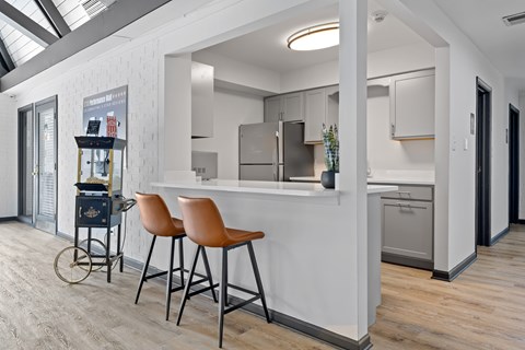A kitchen with a white counter and orange chairs.