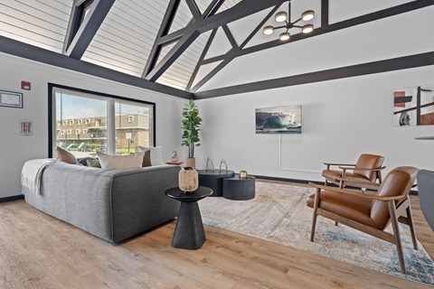 A living room with a grey couch, a brown leather chair, and a small table with a plant on it.