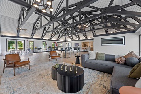 A modern living room with a high ceiling and exposed beams.