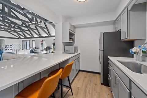 A modern kitchen with a white countertop and orange chairs.