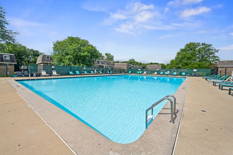 A large outdoor swimming pool with a blue tiled edge and a metal handrail.