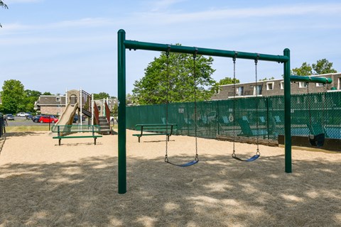 a playground with a swing set and monkey bars in a park at Aspen Ridge Apartments, West Chicago