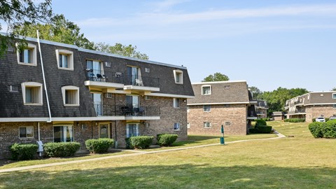 a brick apartment building with balconies and a lawn at Aspen Ridge Apartments, West Chicago, Illinois