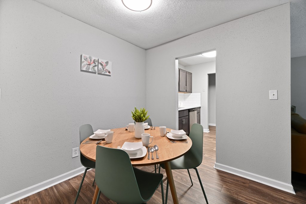 a dining room with a table and chairs and a kitchen in the background at Premier Apartments, Austell, Georgia
