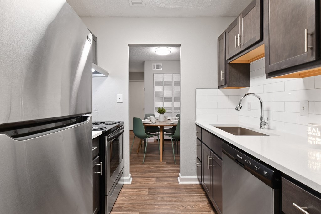 a kitchen with dark cabinets and white countertops at Premier Apartments, Georgia