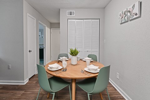 a dining area with a wooden table and green chairs at Premier Apartments, Austell, GA