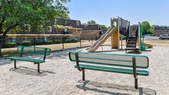 a playground with a slide and benches in a park