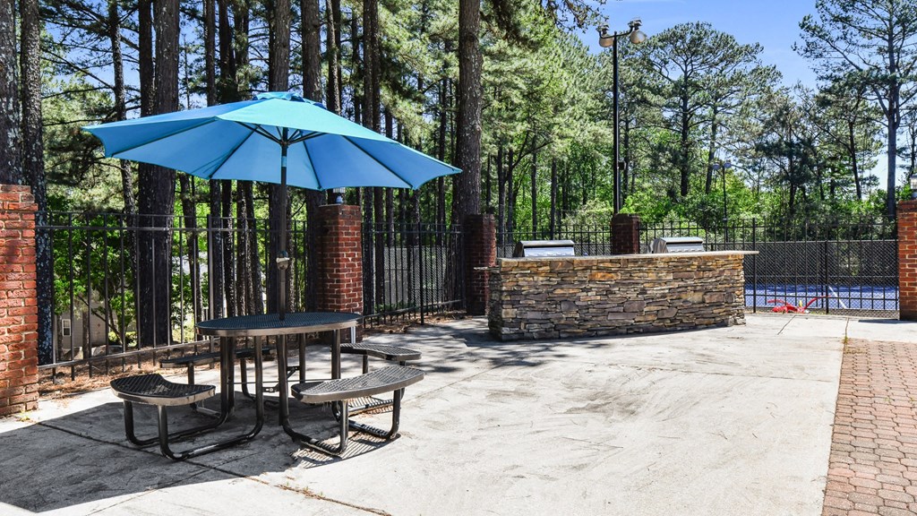 a patio with a table and chairs and an umbrella next to a pool at 300 Riverside Apartments, Austell, GA, 30168