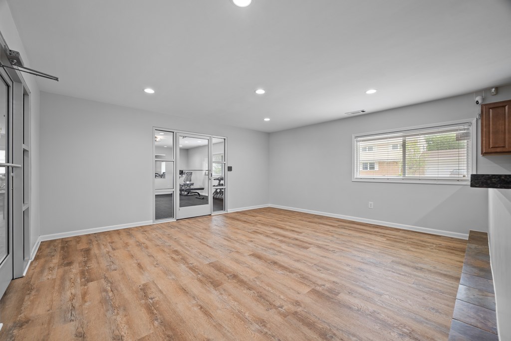 A spacious room with wooden flooring and a large window.