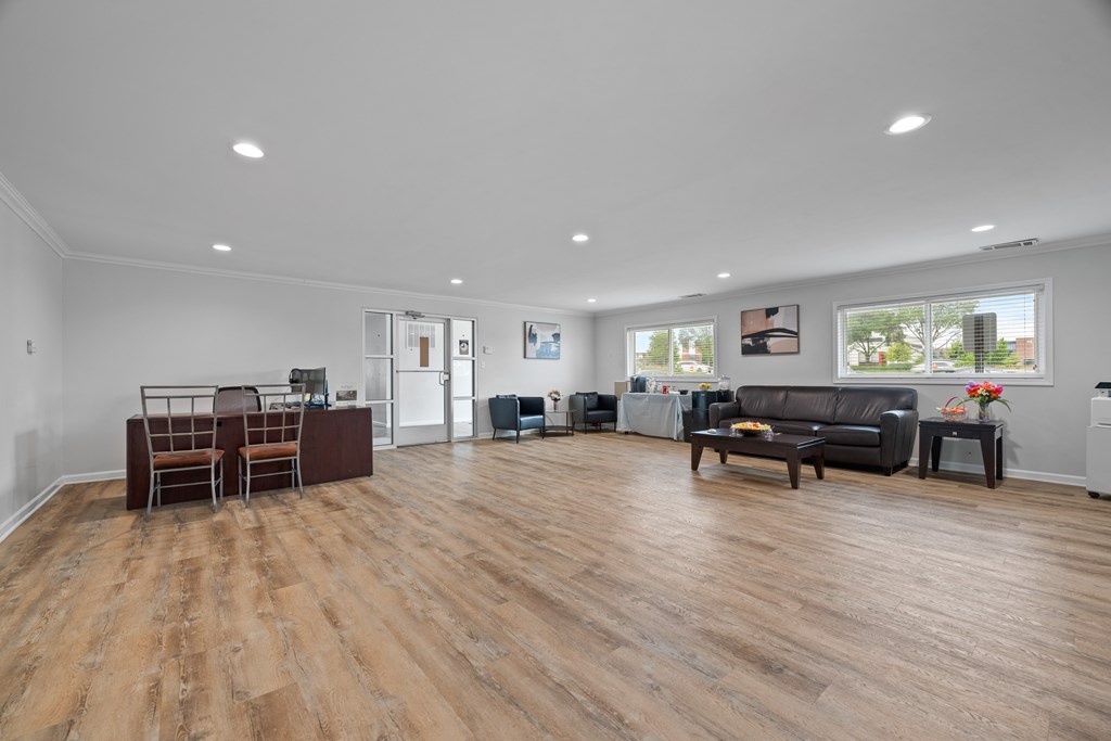 A living room with a black couch and wooden floors.