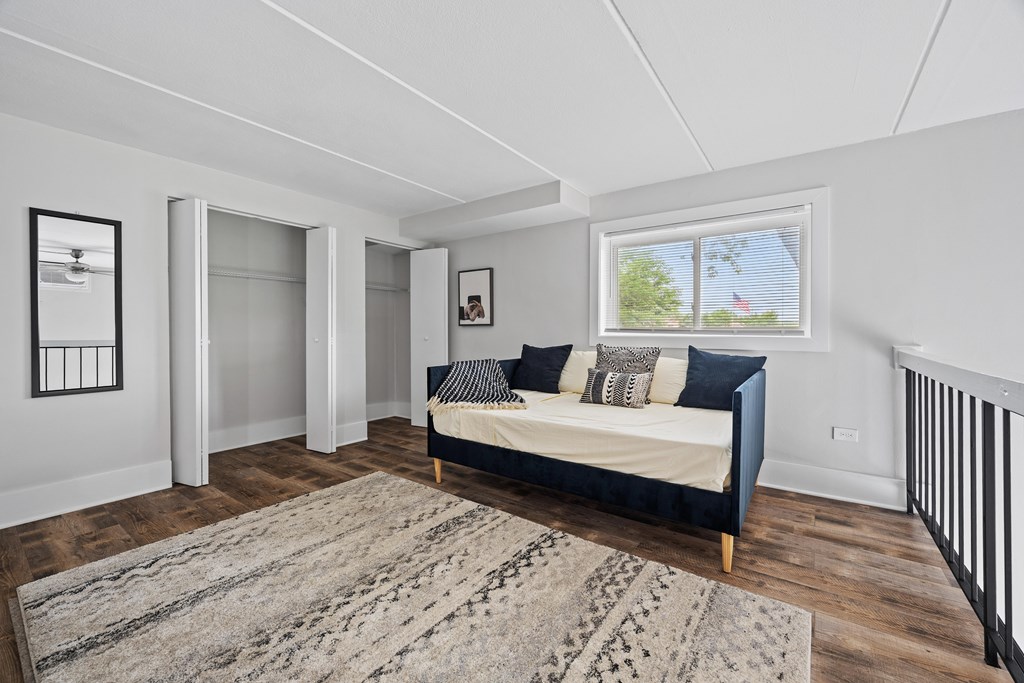 A bedroom with a bed, a rug, and a window.