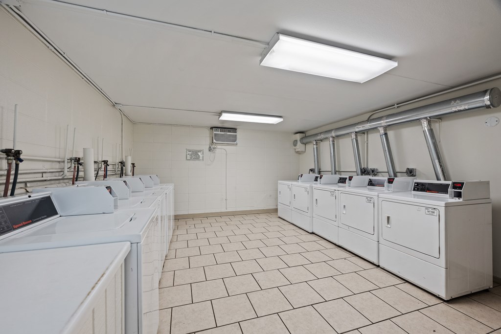 A room with white tiled floors and white walls with industrial equipment.