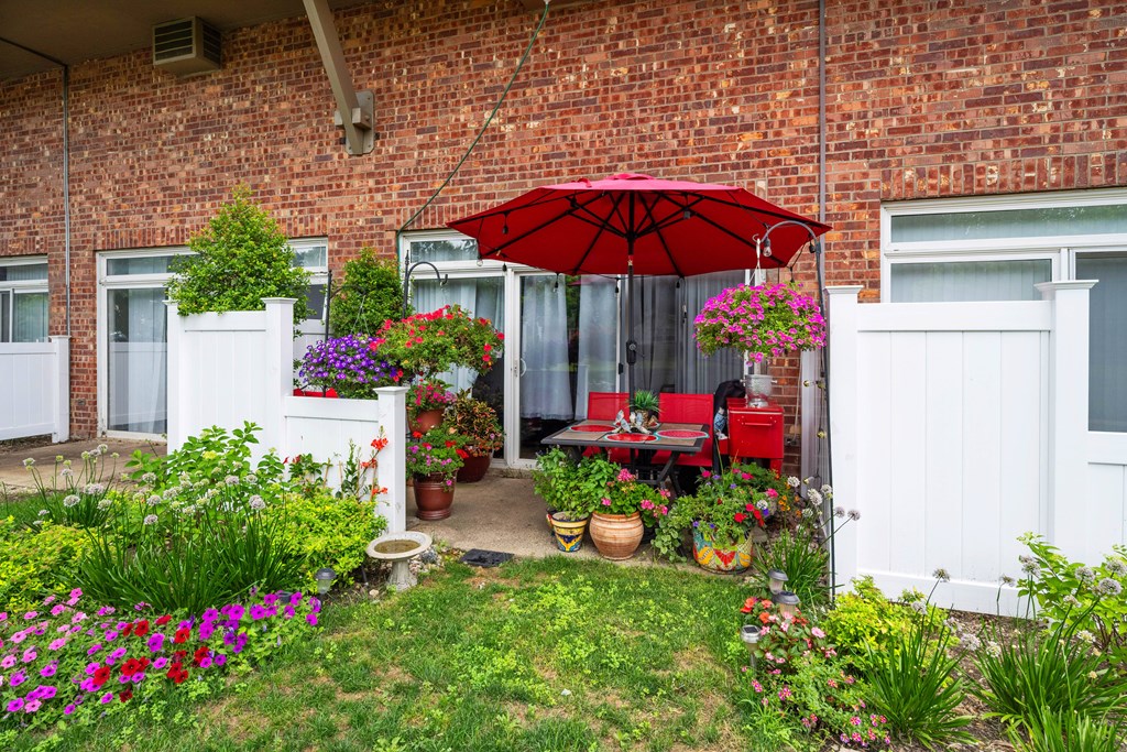 A red umbrella is on a table outside a house.