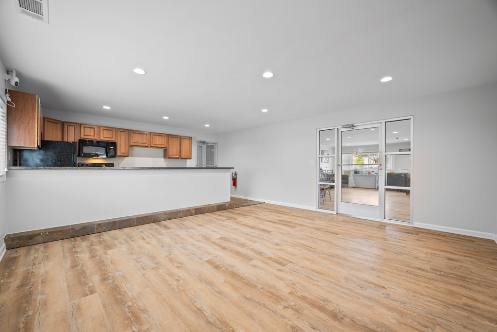 A spacious room with wooden flooring and a kitchen area with a microwave and oven.