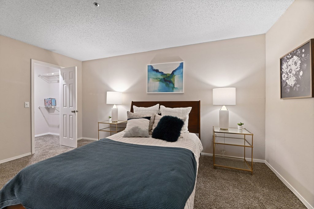 a bedroom with a bed and two night stands with lamps at 300 Riverside Apartments, Austell, GA