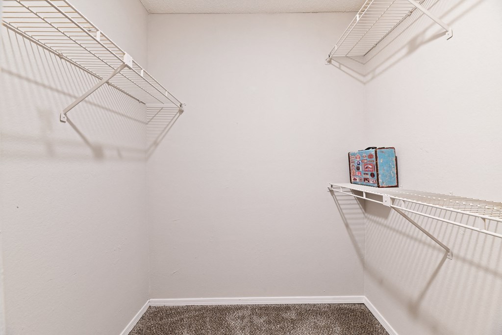 a walk in closet with two shelves and a shelf with a suitcase on it at 300 Riverside Apartments, Austell, GA 30168