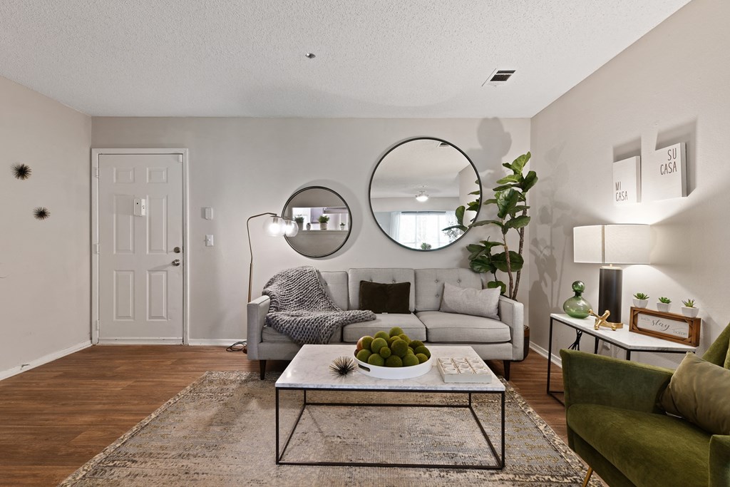 a living room with a couch coffee table and two mirrors at 300 Riverside Apartments, Austell, 30168