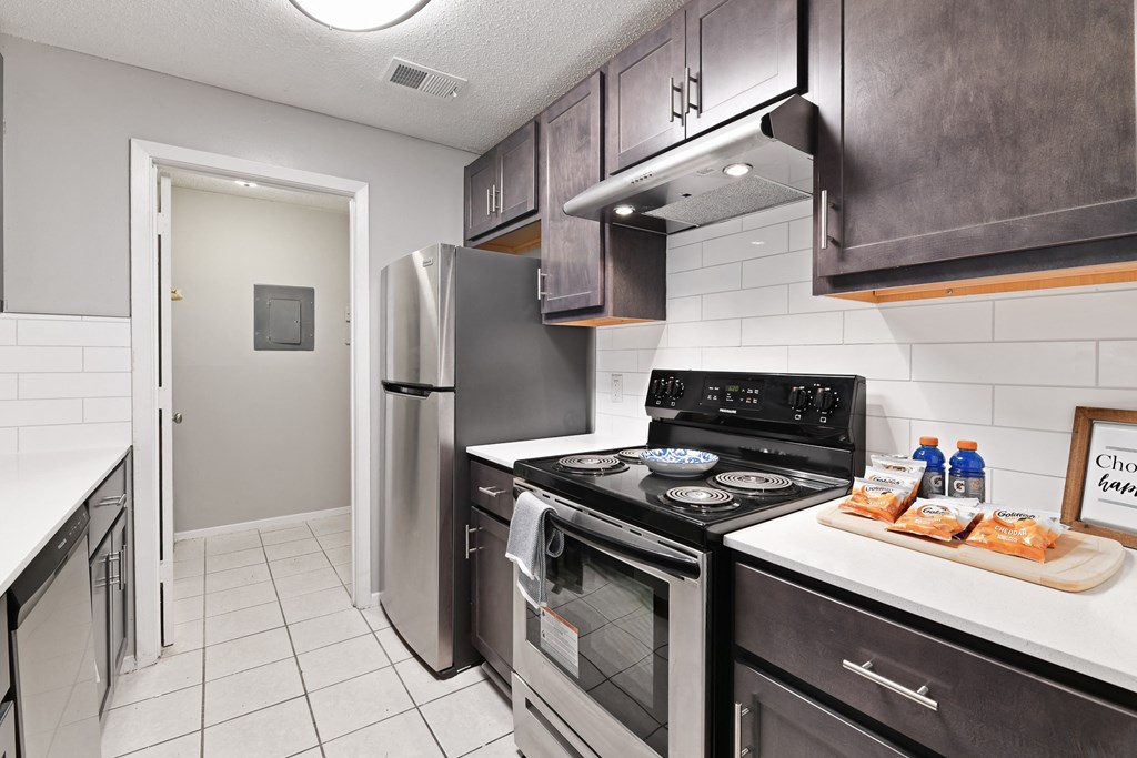 a kitchen with black cabinets and stainless steel appliances at Waldan Pond Apartments, Acworth