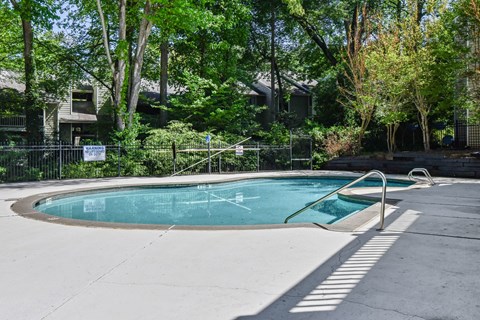 a swimming pool with a fence and trees in the background at Waldan Pond Apartments, Georgia