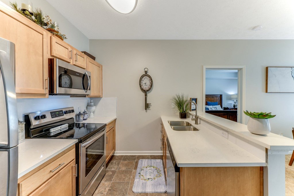 Open kitchen with stainless steel appliances and wooden cabinets at The Reserves of Thomas Glen, Shepherdsville, KY, 40165