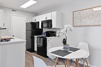 A newly renovated kitchen and dining area with black appliances and white cabinets at Trinity Lakes Apartments Columbus Ohio 43225