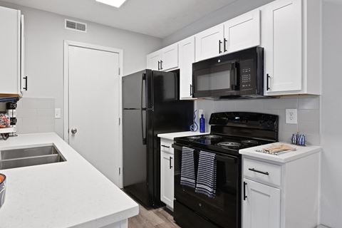 Updated kitchen with white cabinets and black appliances at Trinity Lakes Apartments in Columbus Ohio 43228