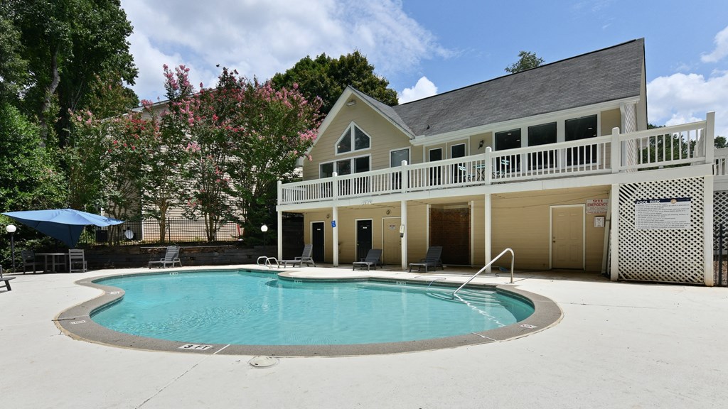 the pool is in front of a large house with a porch