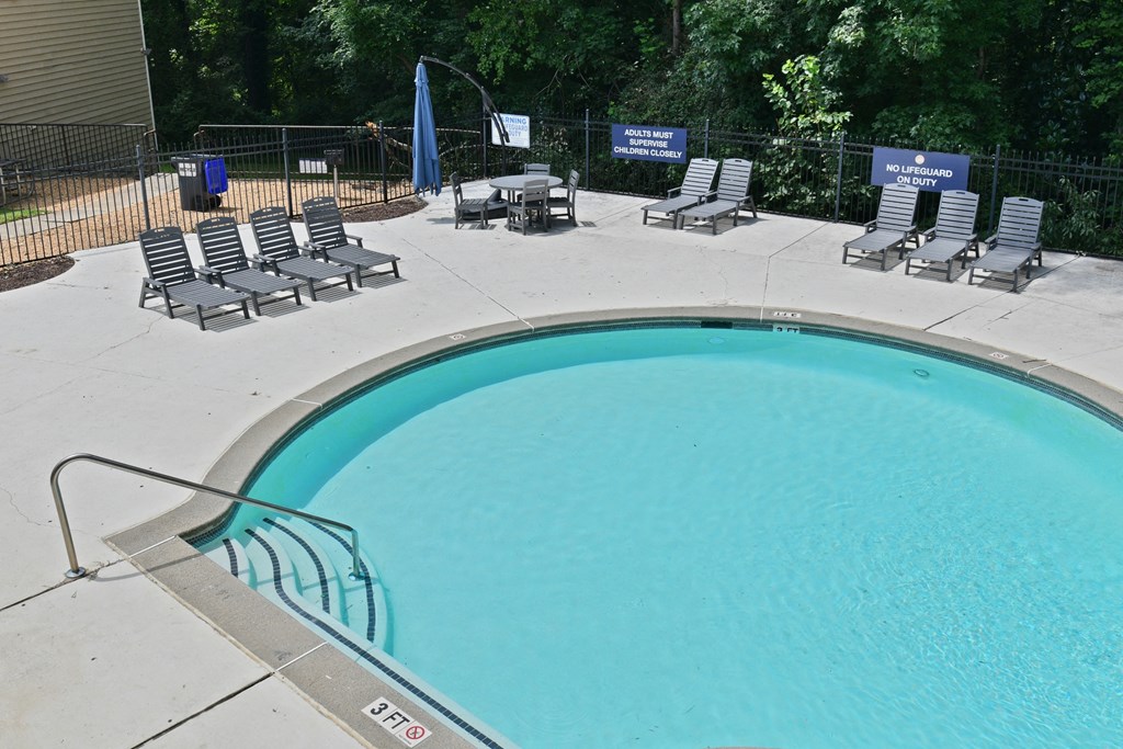 a swimming pool with chairs and a fence around it