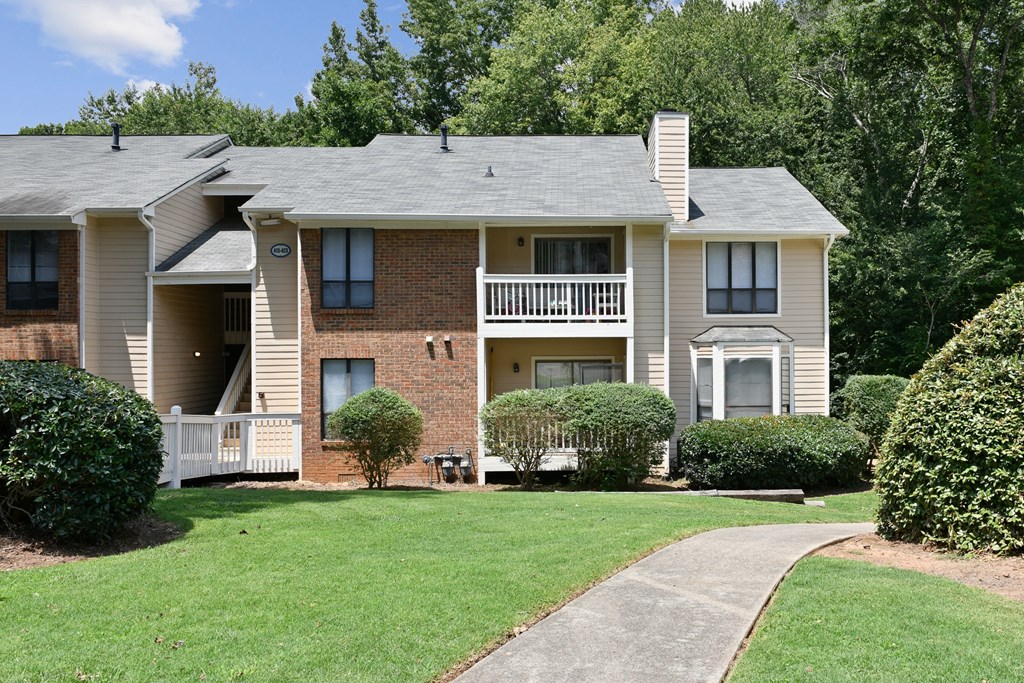 an apartment building with a lawn and a sidewalk in front of it