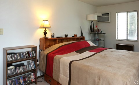 a bedroom with a bed and a shelf with dvds