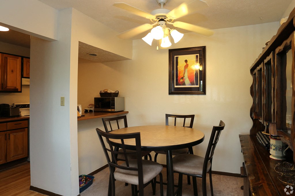 a dining area with a table and chairs and a ceiling fan