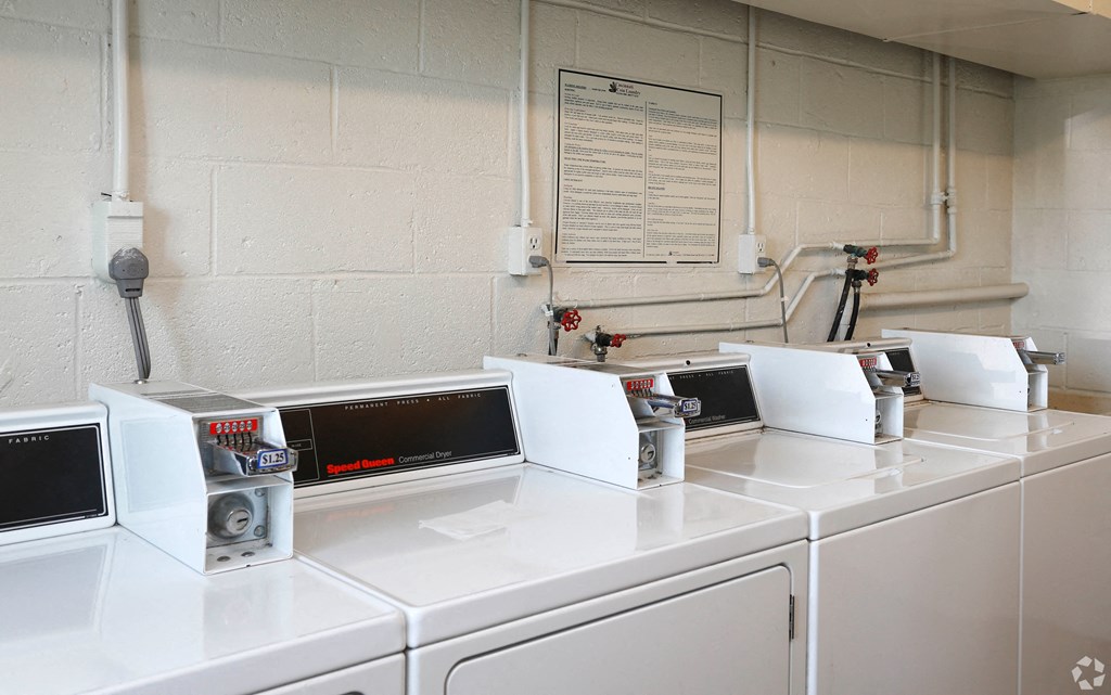 a row of washers and dryers in a laundry room