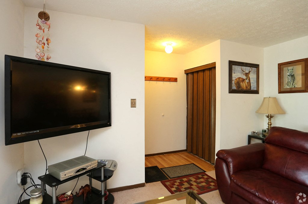 the living room has a large screen tv and a leather couch
