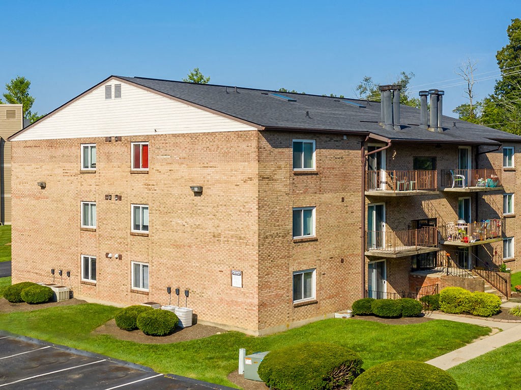 a brick apartment building with balconies and grass