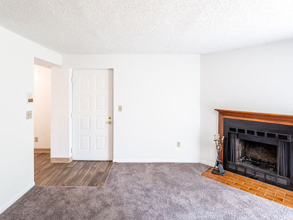 an empty living room with a fireplace and a door