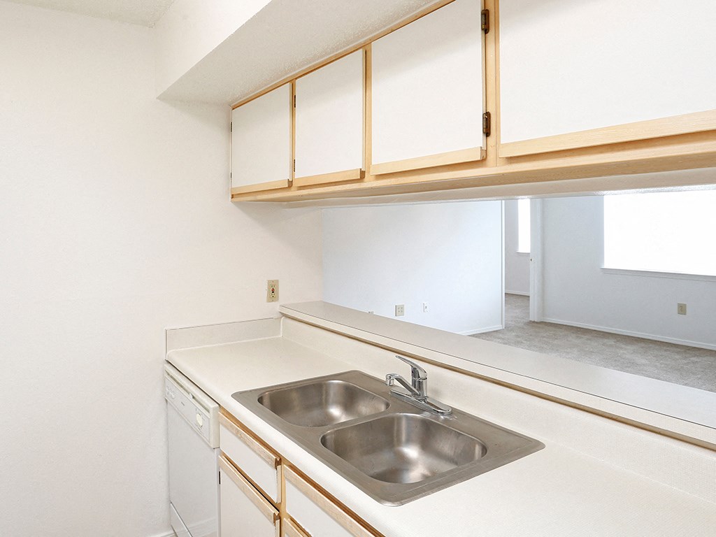 an empty kitchen with a sink and white cabinets