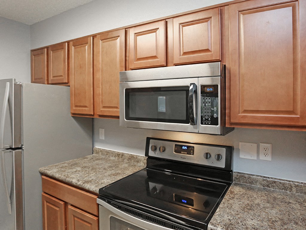 a kitchen with a stove and microwave and wooden cabinets