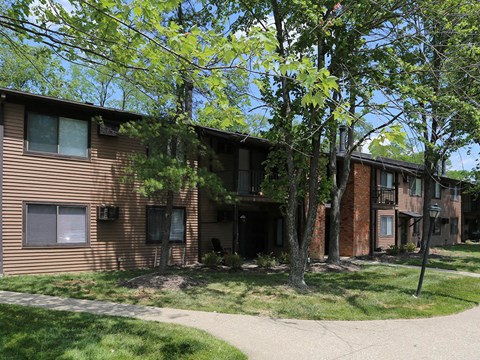 the front of an apartment building with trees and a sidewalk