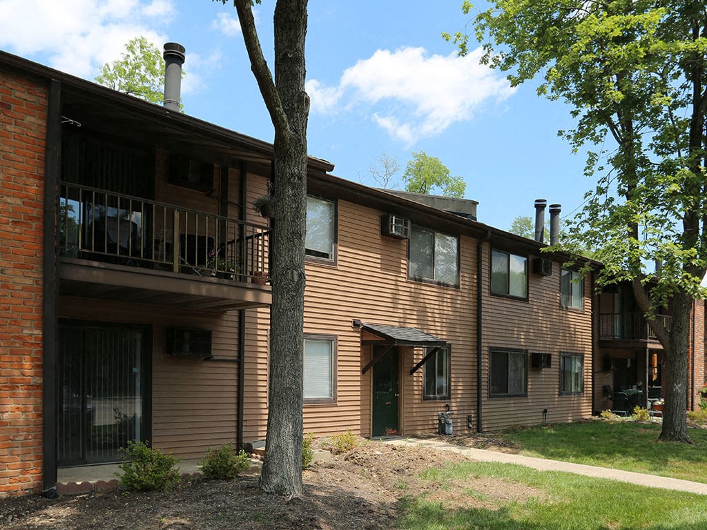 the exterior of a large apartment building with trees and a sidewalk
