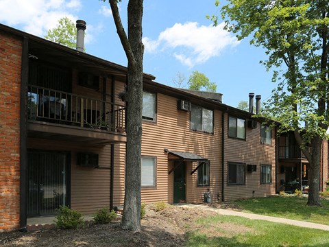 the exterior of a large apartment building with trees and a sidewalk