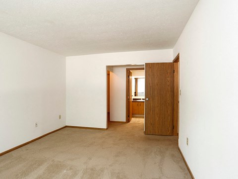 an empty room with carpet and a door to a bathroom