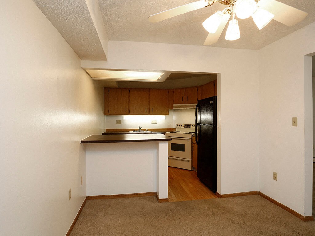 an empty kitchen with a black refrigerator and a sink