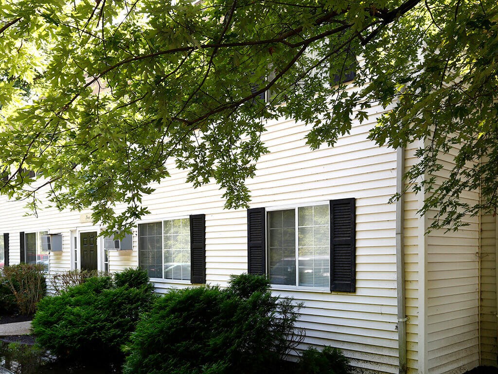 the side of a white house with black window shutters