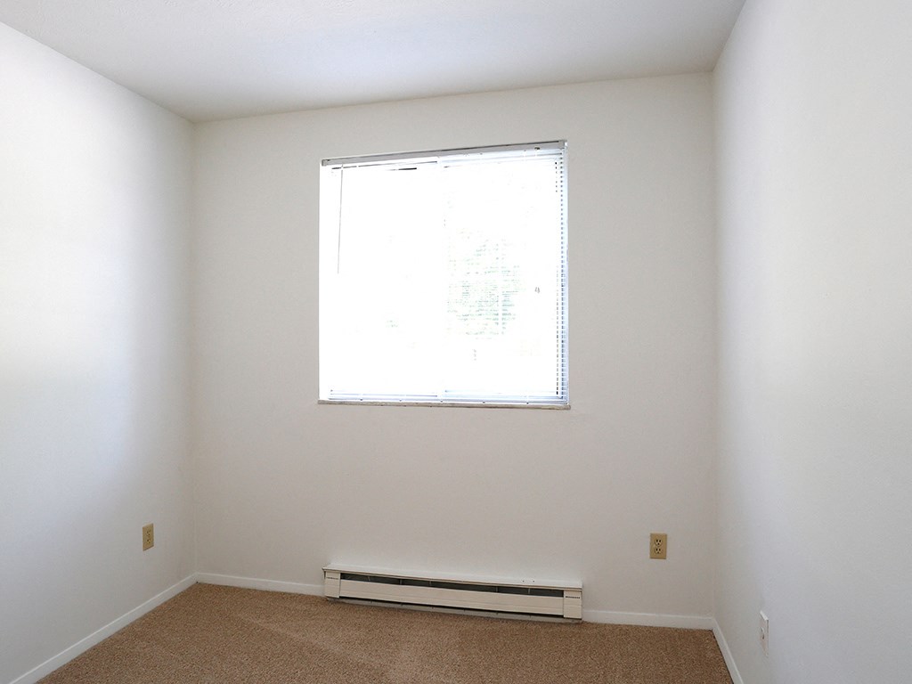 an empty room with a window and white walls